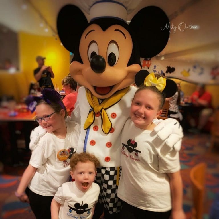 three children, two girls and one boy , with Mickey Mouse
