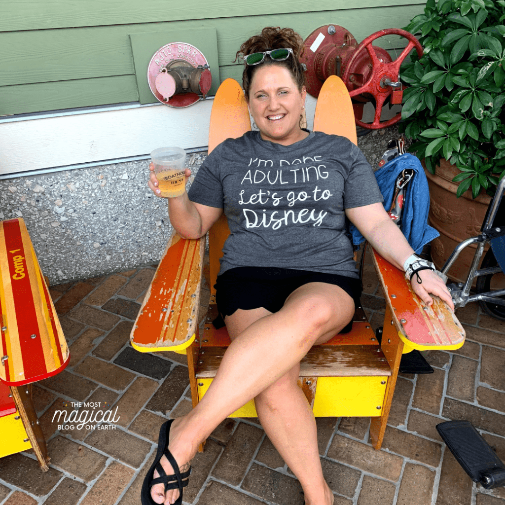 woman in gray shirt and black shorts sitting in an orange and yellow chair holding a drink